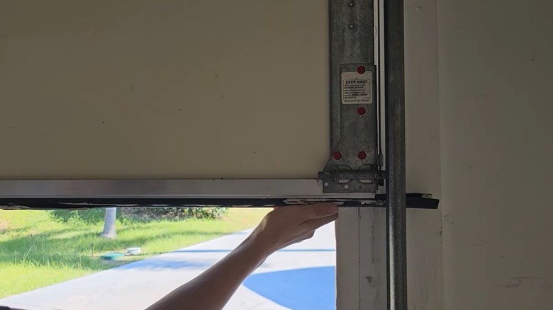 hand realigning bottom seal of garage door