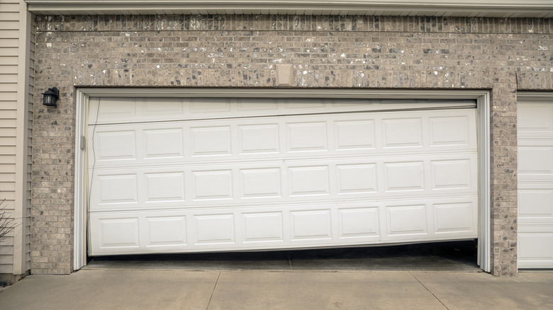A cream colored garage door that is out of track