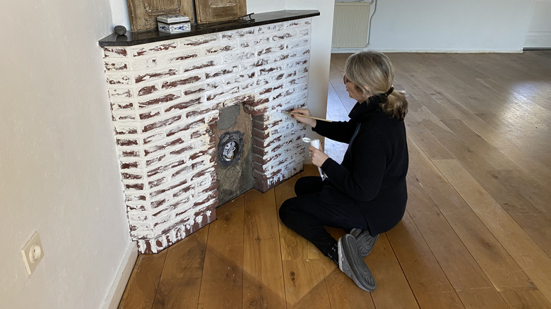 Woman applying a new surface to fireplace bricks