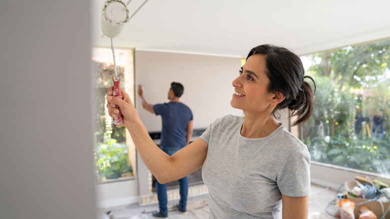 Couple painting a room, including a wall with a fireplace
