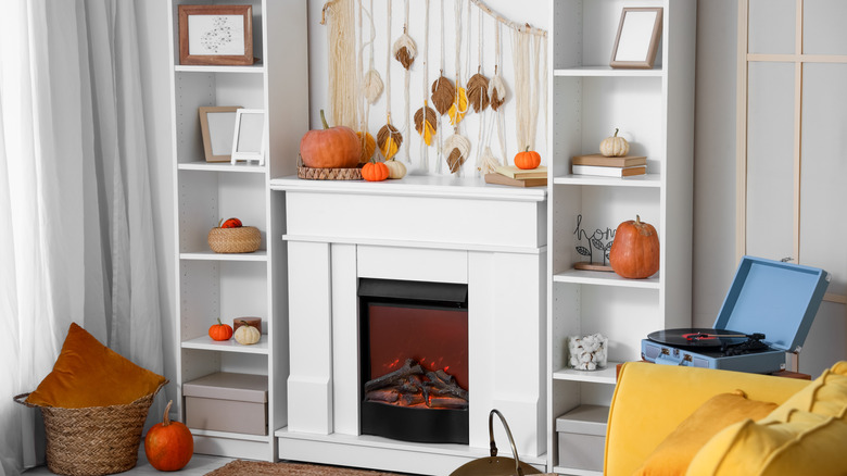Two narrow bookshelves flanking a fireplace with seasonal decor on them