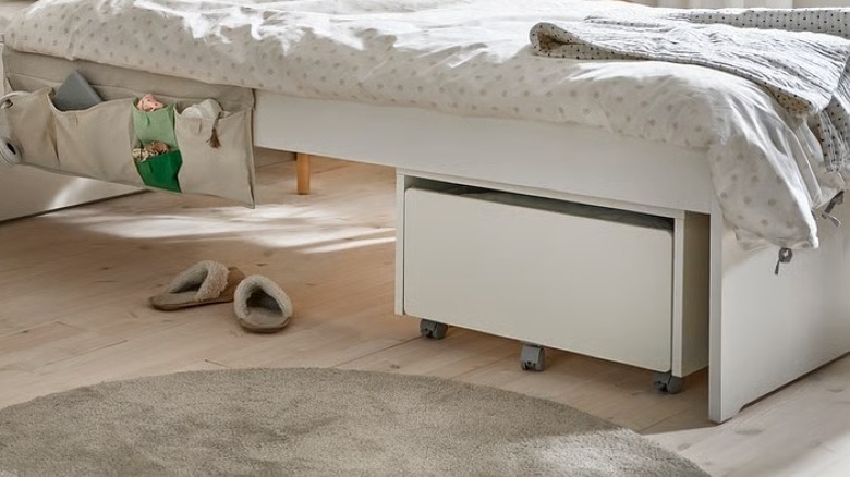 A wooden under-bed storage bin with wheels
