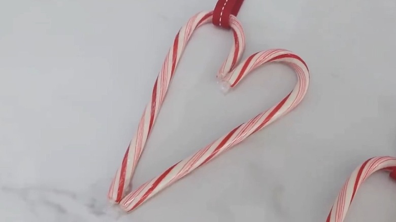 Heart-shaped candy cane ornament on a white table