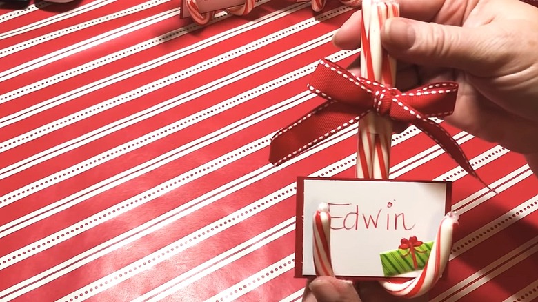 Person holding candy cane place card holder with a name tag in it