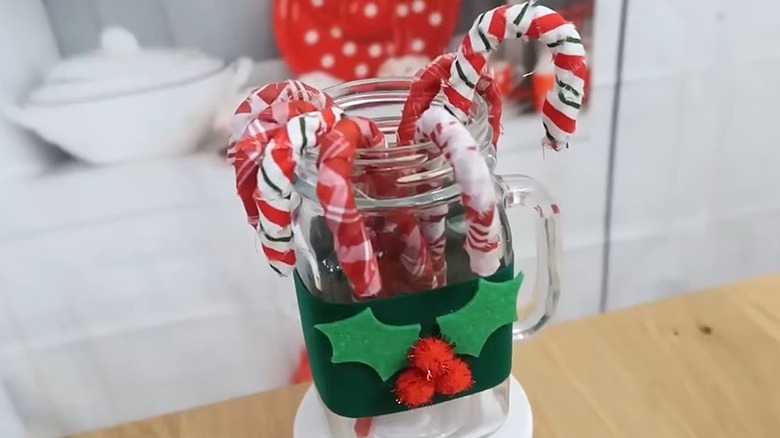 Fabric-covered candy canes in a glass jar decorated with felt holly