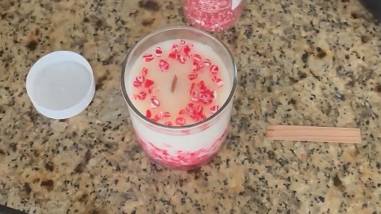 Close-up of a candle made with crushed peppermint candy with a wick next to it