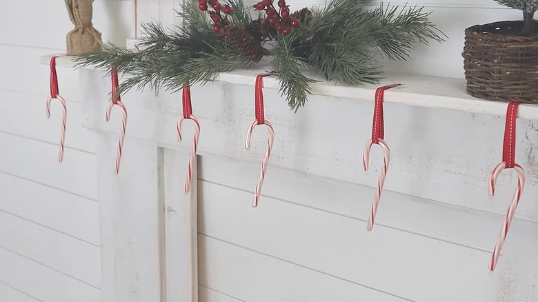 Candy canes hung up by ribbon loops on a fireplace mantel