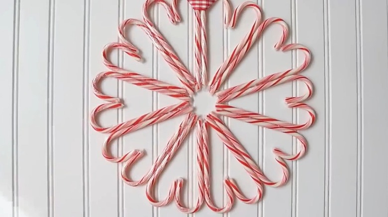 Close-up of a candy cane wreath hanging on a white wall