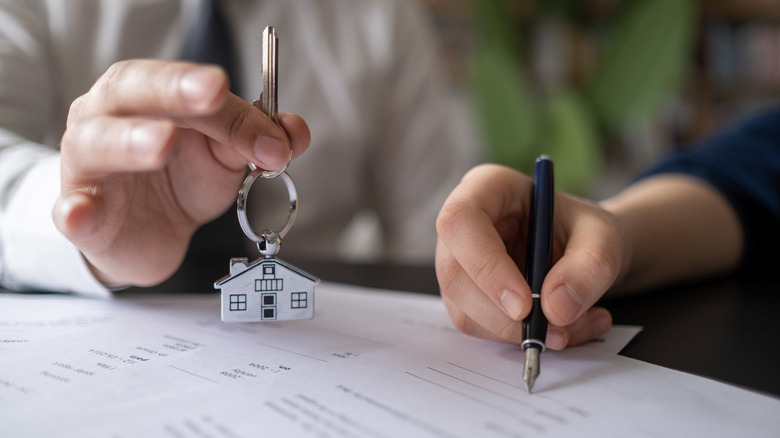 Property manager holding filing keys to customer after signing rental lease