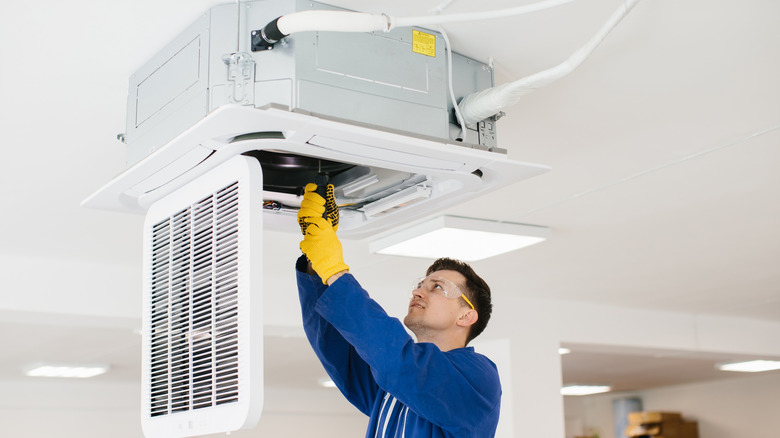 Hvac technician installing an air conditioning unit on the ceiling of a building