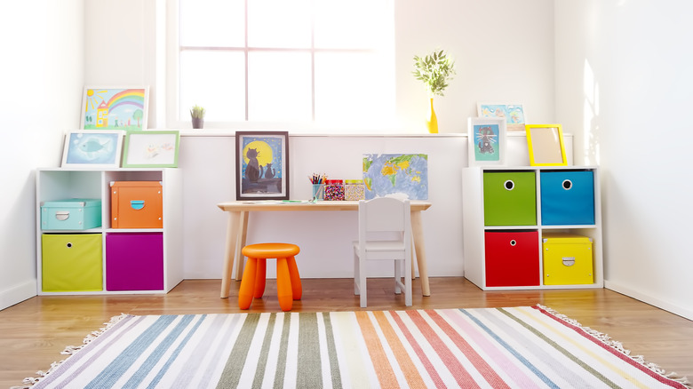 Clean, tidy playroom with colorful storage bins, a striped rug, and a kid-sized table and chairs