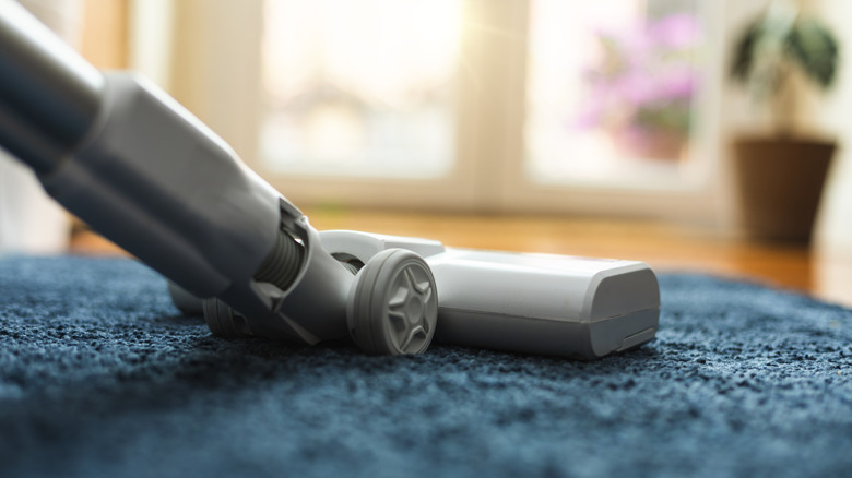 Vacuum going over a blue rug
