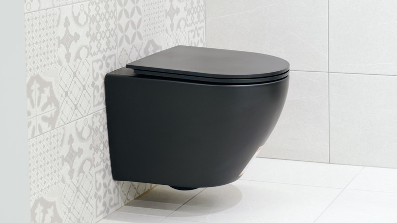 Black wall-hung toilet in bathroom