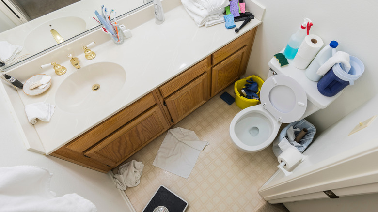 Small, cluttered bathroom with compact round bowl toilet