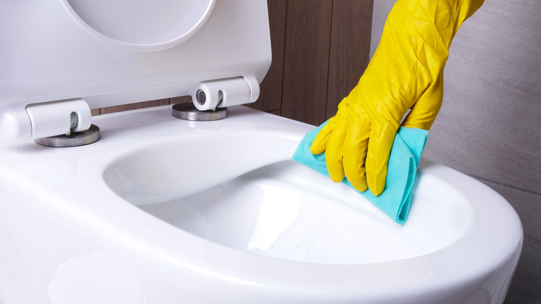 gloved hand cleaning rimless toilet