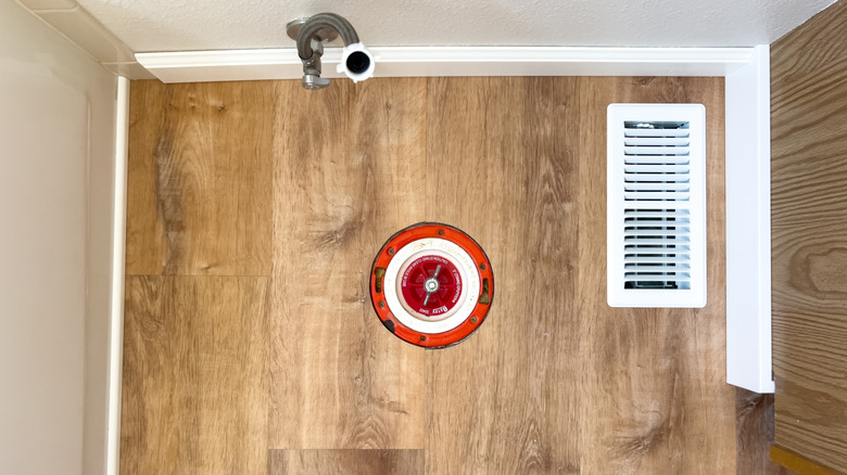 Top shot of the toilet flange covering the drain pipe in a new bathroom and the water inlet line
