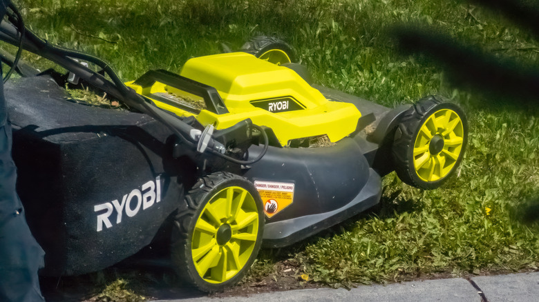 A Ryobi lawn mower being pushed onto a lawn