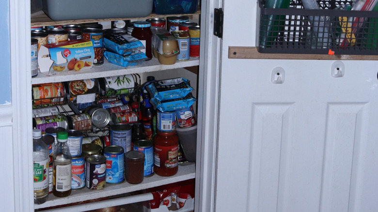A cluttered pantry item with many cans and bottles