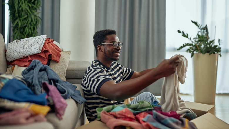 Man sorting through clothes to donate