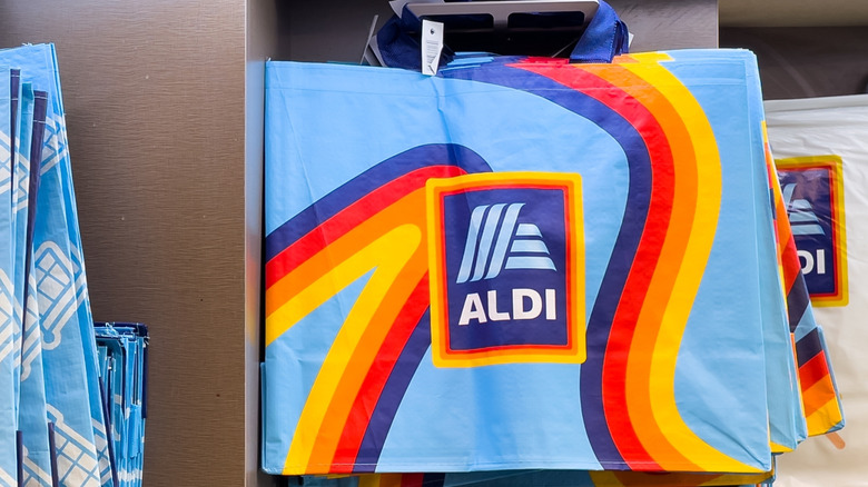 A reusable Aldi grocery bag hanging in a store