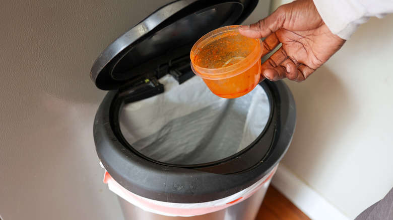 A person throwing a way a stained food container