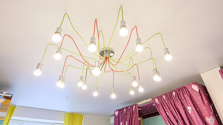 A funky overhead light fixture featuring tons of exposed bulbs in a child's bedroom