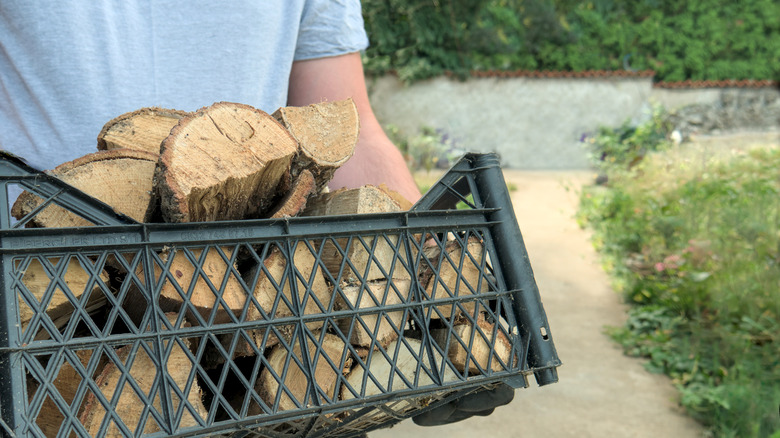 Close up of person carrying box of firewood