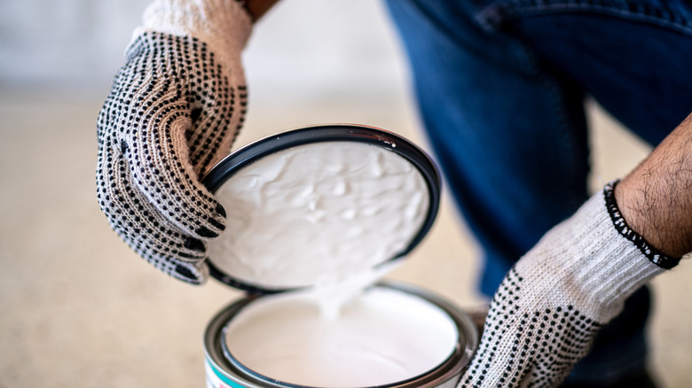 Person opening white paint can