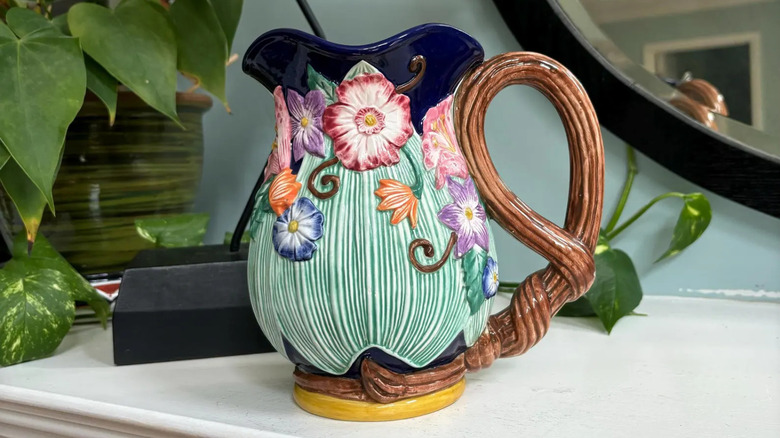 A Fitz & Floyd floral vase in front of a plant and a mirror