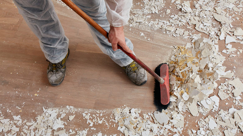 Close-up of a person sweeping up mess from a home renovation