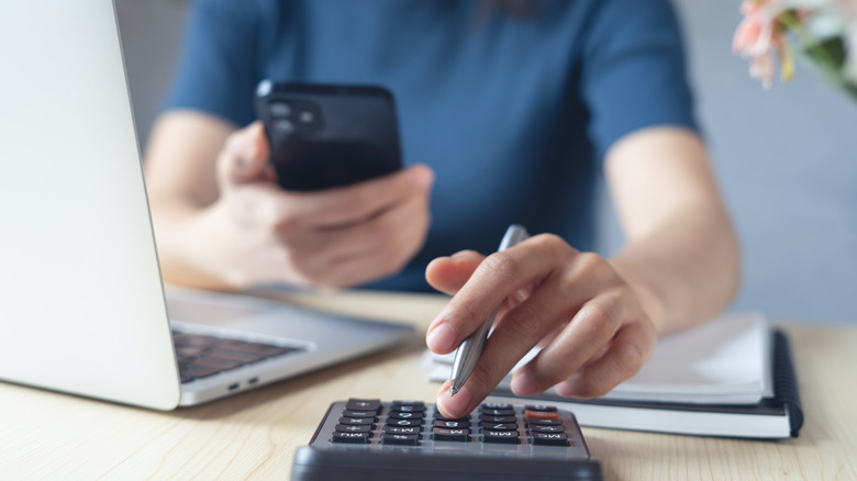 Close-up of a person budgeting with a phone and calculator