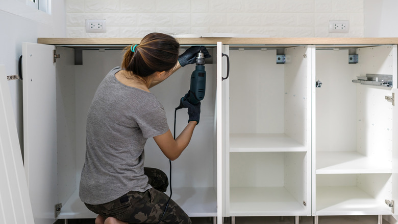A woman installing kitchen units
