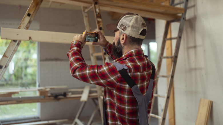 A man taking pictures mid-renovation work with a smartphone