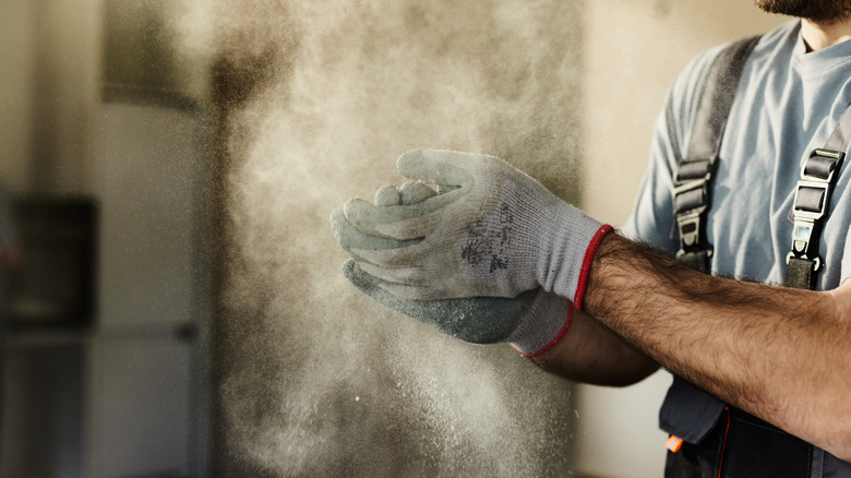 Close-up of a person clapping gloved hands and expelling lots of dust