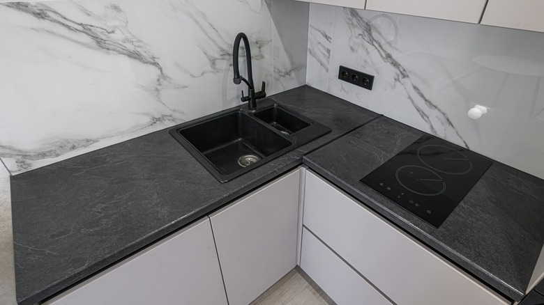Charcoal countertop contrasts dramatically with veined white marble backsplash.
