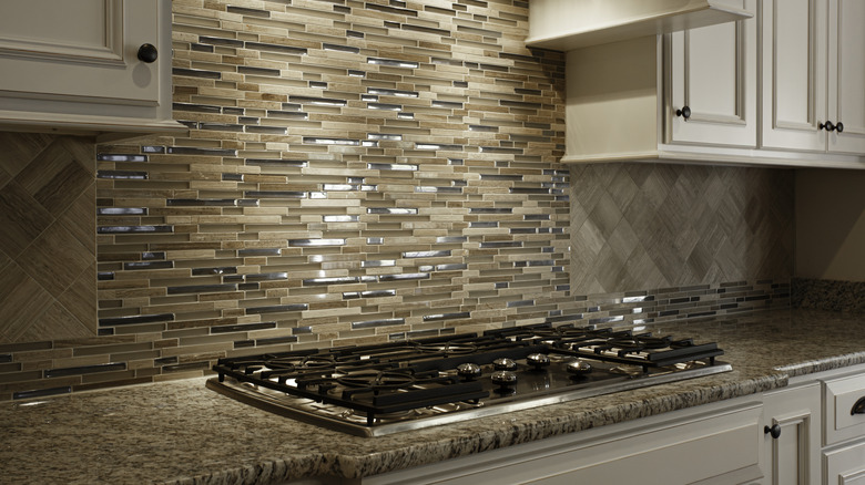 Several types of neutral finishes are seen in the range-hood area of this kitchen.