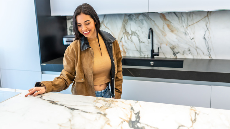 Woman looks at kitchen island countertop.