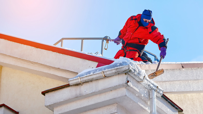 Worker removing snow from a building