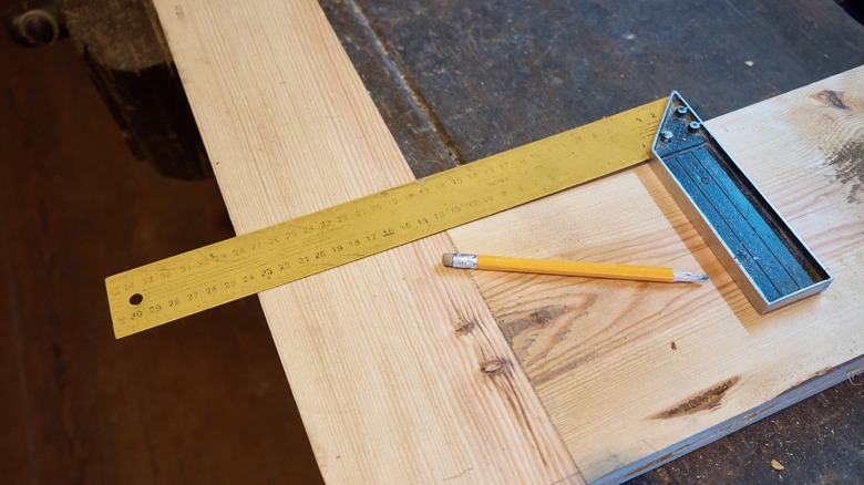 carpenter's square and pencil lying on a board