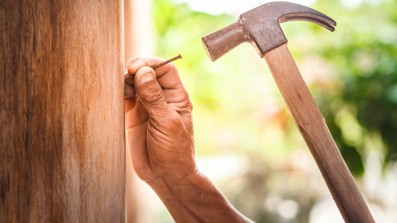 close up of person hammering nail into wood