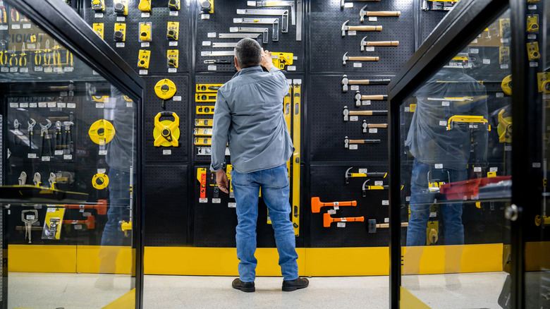 person standing in an aisle in a hardware store looking at tools