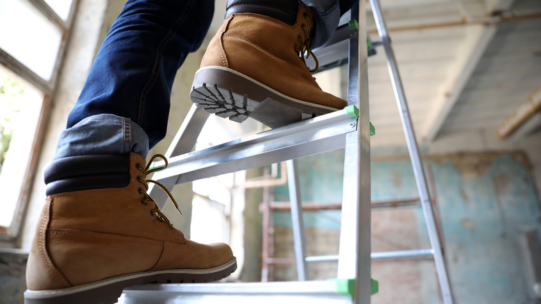 close up of person's feet in boots climbing up a ladder