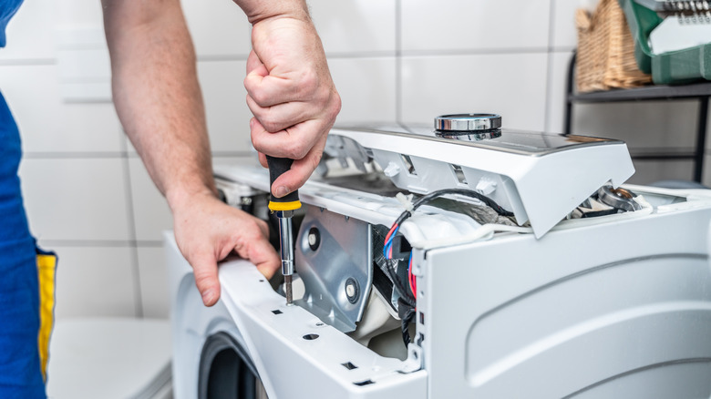 person working on an appliance with a screwdriver