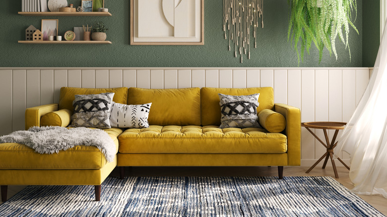 A living room scene with mustard yellow velvet sofa and area rug on the floor