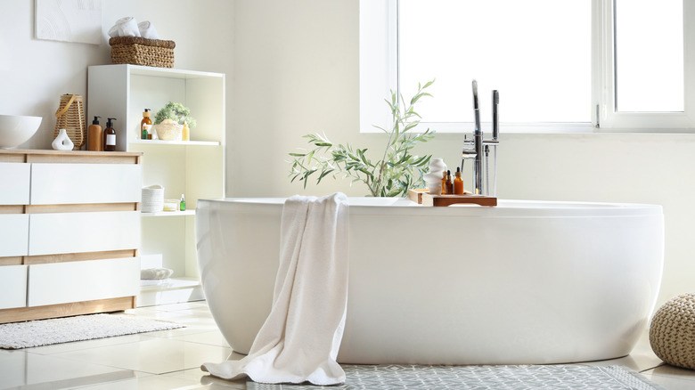 A beautiful bathroom scene including a freestanding bath, drawer cabinet, and open-shelving with a woven basket on top