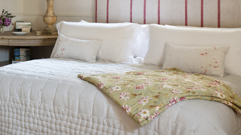 King sized bed with white quilt and floral throw