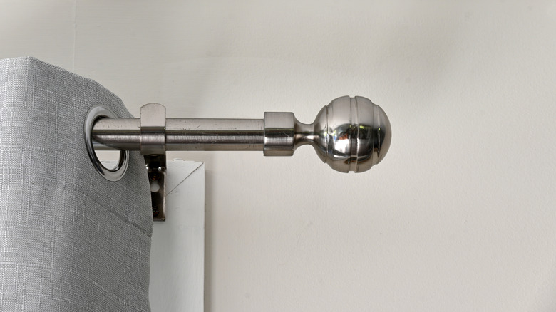 A metal curtain pole with a decorative, ball-shaped finial