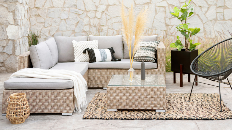 A rattan outdoor furniture set layered with cushions in differing designs