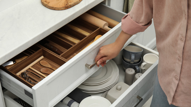 Person opening kitchen drawer organized with an internal divider