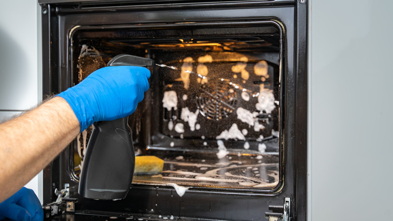 Person spraying the oven with cleaner